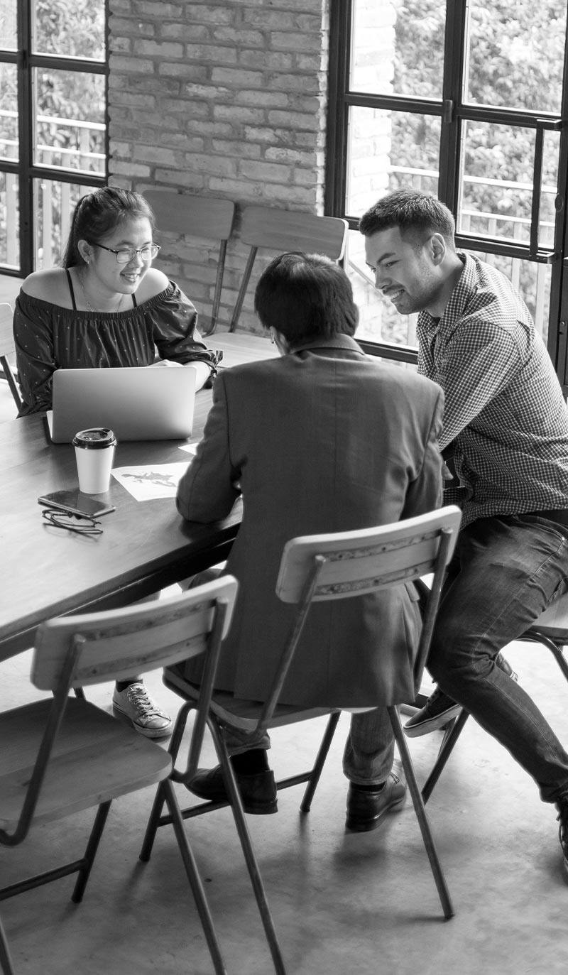 Three people sitting around a table in a modern office setting.
