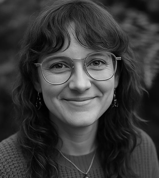 Black and white portrait of a woman wearing glasses with a blurred natural background
