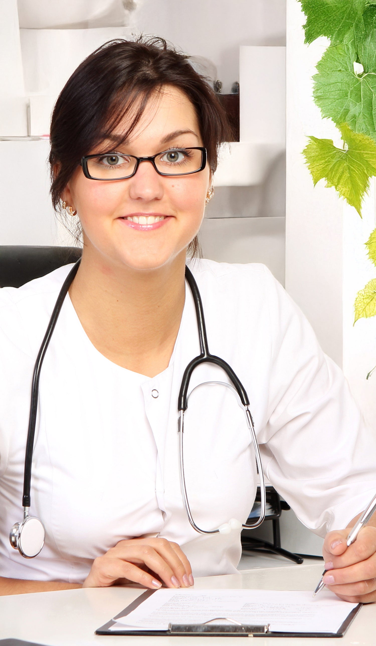 Doctor with a stethoscope around her neck, sitting at a desk with a whiteboard in the background writing a prescription for a nicotine vape.
