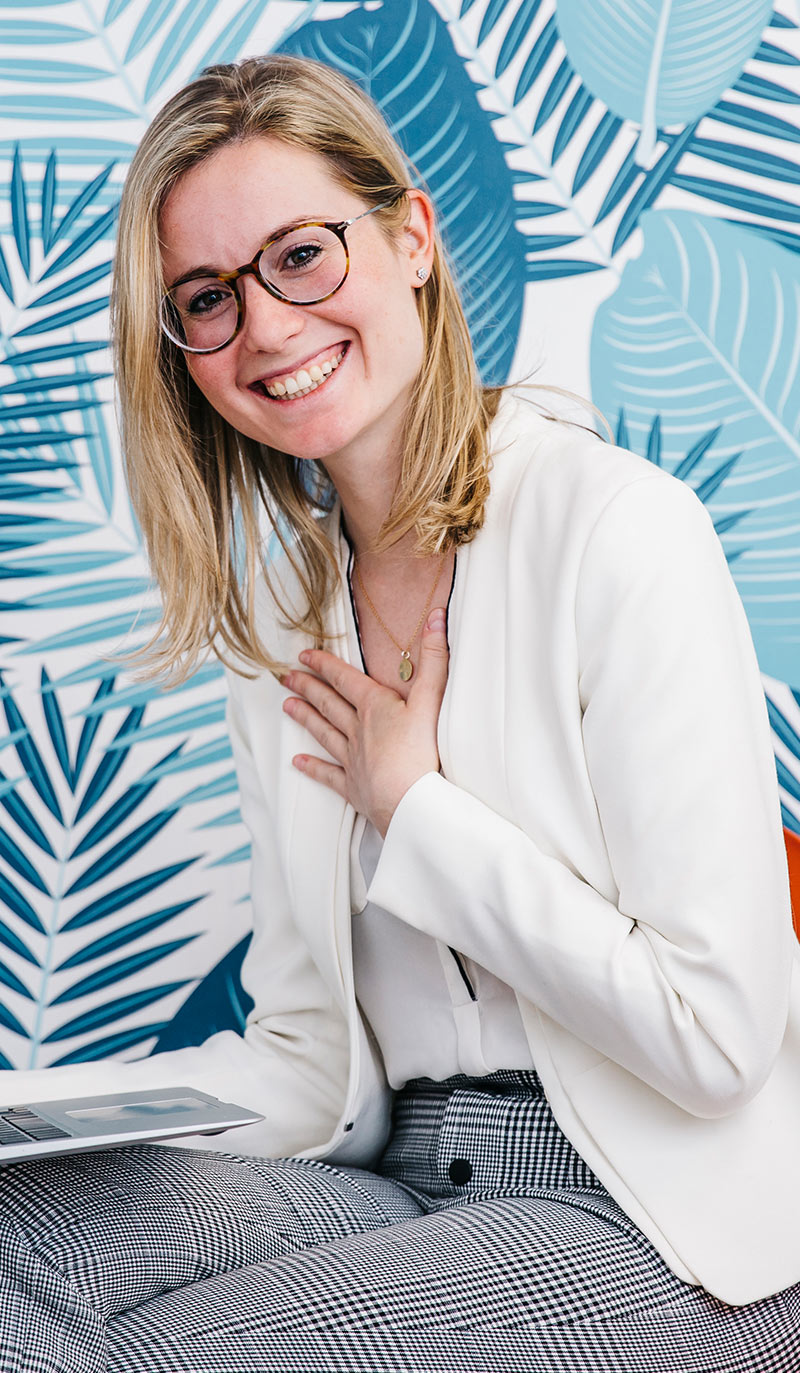 Doctor in a white blazer sitting against a blue patterned wall talking to a patient about nicotine vapes to quit smoking