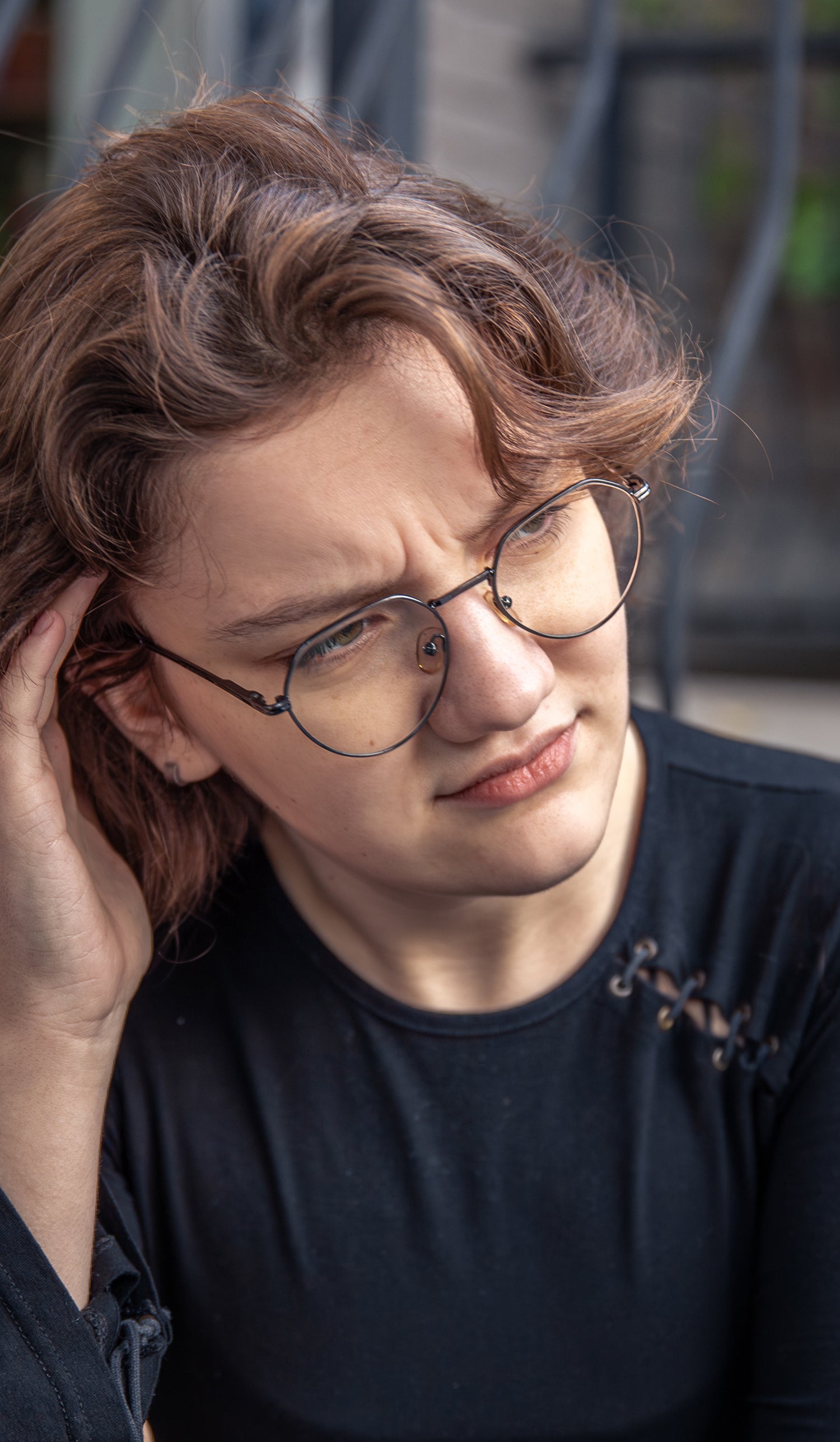 Person wearing glasses with a concerned expression about smoking withdrawls, holding head with hand.