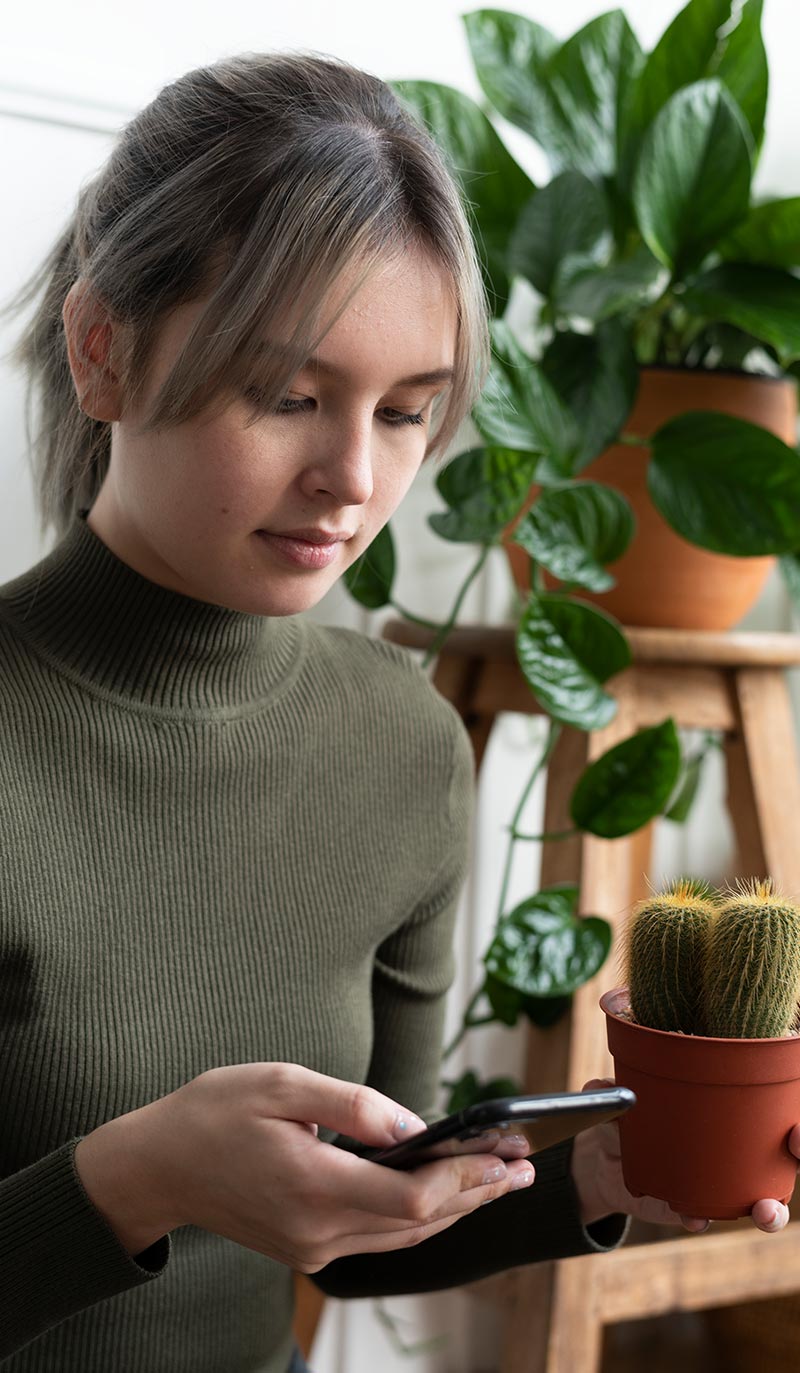 Woman using a smartphone indoors with plants in the background